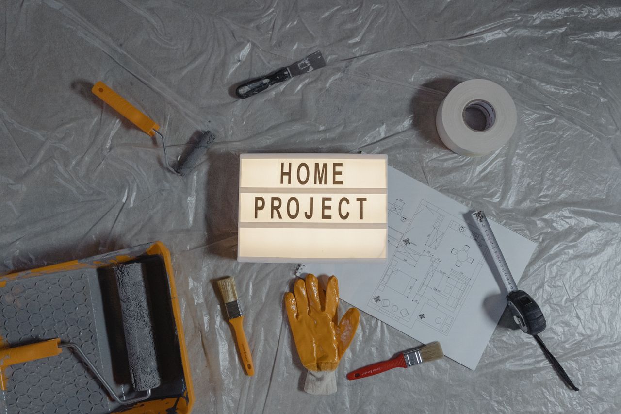 services-06 Flat lay of home improvement setup with tools, gloves, and floor plan for DIY projects.