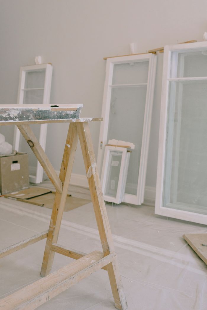 Interior of room with wooden workbench and windows removed from hinges with white frame placed near wall in light room during repair works
